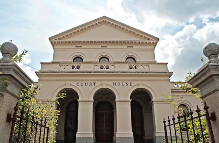 Front view of a classical courthouse building under partly cloudy sky
