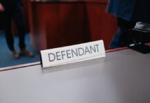 Damon Jones & Marves Fairley Released on Bail After Pleading Not Guilty in NBA Betting Scandal A courtroom setting with a defendant sign on the table.