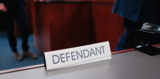 A desk sign labeled “Defendant” inside a courtroom setting.