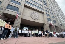People gathered outside a large government building holding signs during a public demonstration.