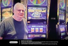 Barnett T., the Empire City Casino player who won a $2.99 million jackpot, standing next to the Wheel of Fortune Triple Stars slot machine.