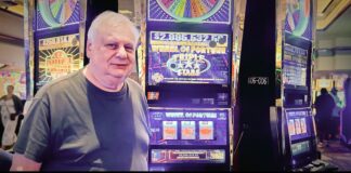 Barnett T., the Empire City Casino player who won a $2.99 million jackpot, standing next to the Wheel of Fortune Triple Stars slot machine.
