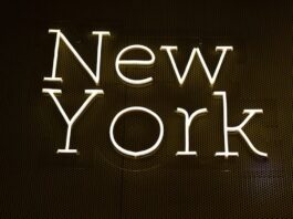 Bright neon-style sign spelling out “New York” on a dark wall background.