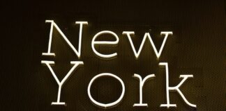 New York Bill Proposes Banning Sportsbooks From Offering Problem Gamblers Help Bright neon-style sign spelling out “New York” on a dark wall background.