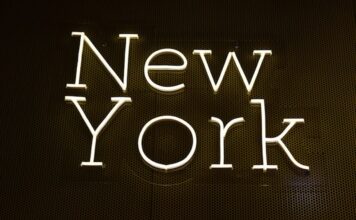 Bright neon-style sign spelling out “New York” on a dark wall background.