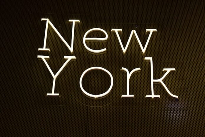 Bright neon-style sign spelling out “New York” on a dark wall background.
