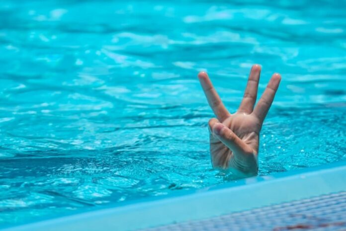 Hand showing three fingers above a swimming pool surface