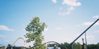 Visitors walk near the Hershey’s Chocolatetown entrance and roller coasters on a sunny day in Hershey, Pennsylvania.