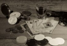 California Bookie Sentenced to Nearly Two Years for Illegal Sports-Betting & Tax Evasion Vintage playing cards, poker chips, and coins on a wooden table symbolizing illegal gambling and betting culture.