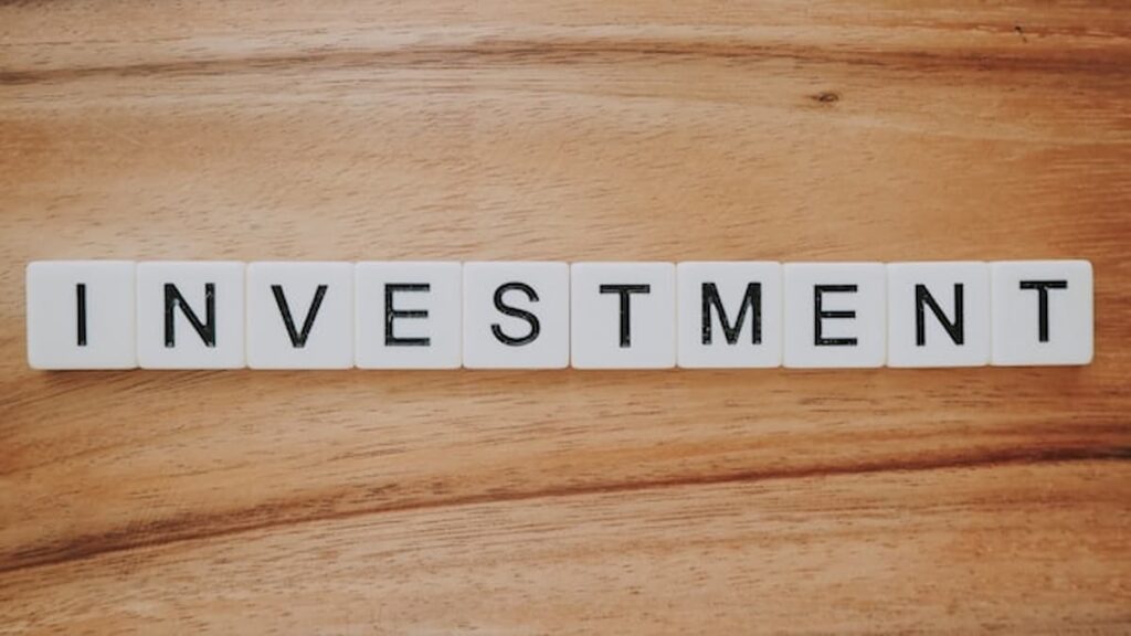 Scrabble letter tiles spelling the word investment on a wooden surface.