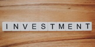 Scrabble letter tiles spelling the word investment on a wooden surface.