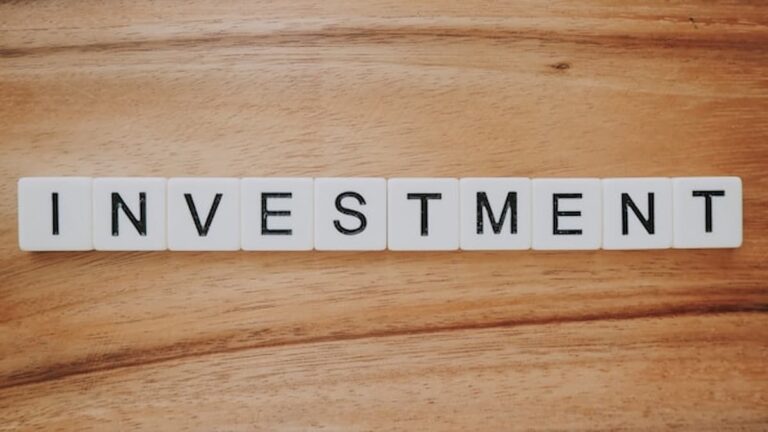 Scrabble letter tiles spelling the word investment on a wooden surface.