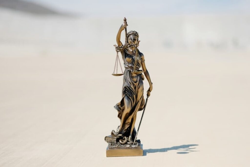 Bronze statue of Lady Justice holding scales and sword outdoors