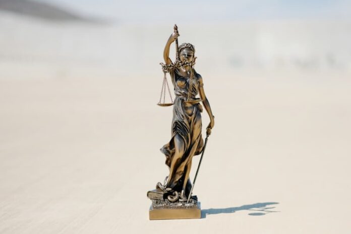 Bronze statue of Lady Justice holding scales and sword outdoors