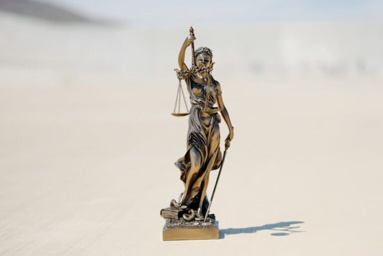 Bronze statue of Lady Justice holding scales and sword outdoors