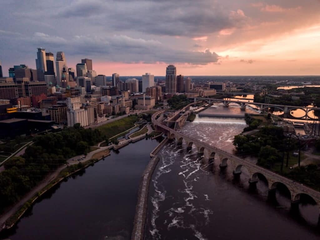 Aerial view of downtown Minneapolis skyline and Stone Arch Bridge at sunset.