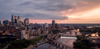 Aerial view of downtown Minneapolis skyline and Stone Arch Bridge at sunset.