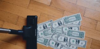 Vacuum cleaner sweeping up dollar bills on a wooden floor, symbolizing stolen money lost to gambling.