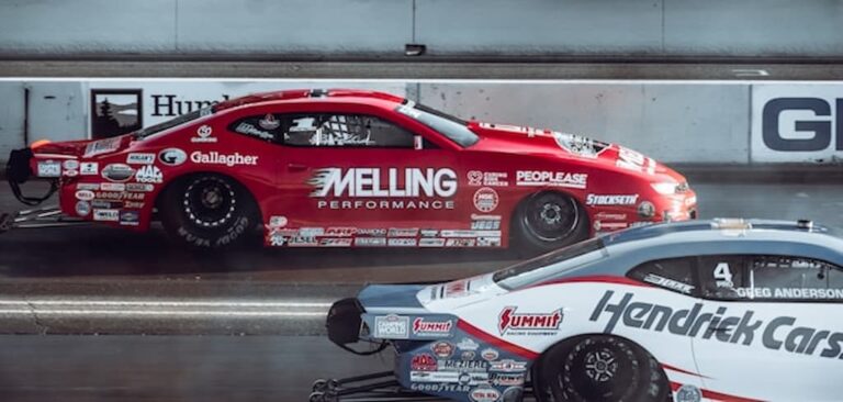 Two race cars driving side by side on a racing track.