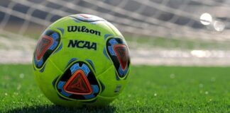 Bright yellow soccer ball on green turf in front of goal