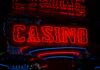 Mount Airy Casino Faces Lawsuit From Male Employee ‘Demeaned for Being White’ & ‘Not Man Enough’ Red neon casino sign glowing against dark background.