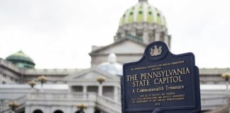 Pennsylvania State Capitol building with a historical marker sign in the foreground.