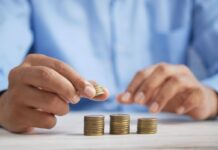 Close-up of a person stacking coins on a desk, symbolizing revenue growth and investment.