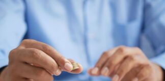 Close-up of a person stacking coins on a desk, symbolizing revenue growth and investment.