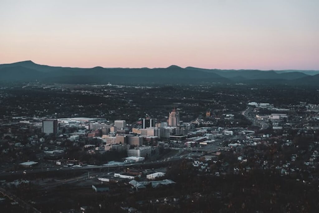 Aerial view of downtown Roanoke, Virginia, surrounded by the Blue Ridge Mountains at dusk.