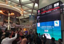 Light & Wonder Reaffirms November Nasdaq Delisting as Legal Pressures Persist A stock exchange trading floor with a large digital display board showing IDX Composite index figures, surrounded by people and media cameras.
