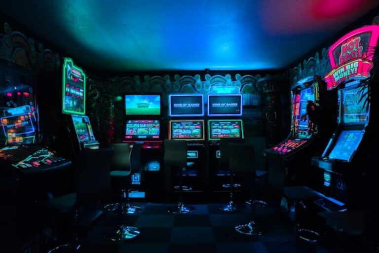 Row of brightly lit gambling-style arcade machines in a dark room.
