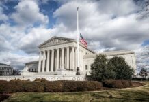 The U.S. Supreme Court building in Washington, D.C., with the American flag at half-mast