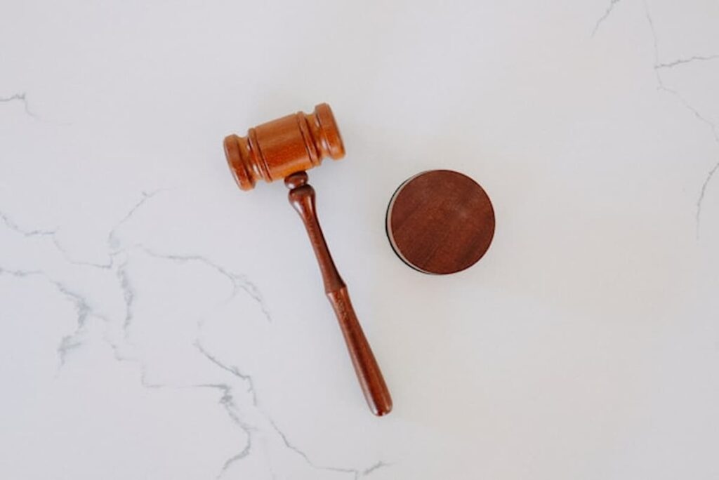 Wooden judge’s gavel and sound block on white marble surface
