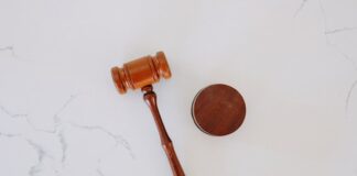 Wooden judge’s gavel and sound block on white marble surface