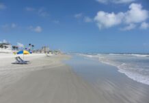 Florida Authorities Seize 22 Illegal Machines, $25K in Cash in Port Orange Raids Sandy beach with umbrellas under a clear blue sky