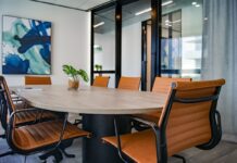 Special Committee Says PENN Board Acted “In Good Faith” in HG Vora Board-Seat Dispute Modern conference room with a wooden table, brown leather chairs, glass walls, and a large abstract painting on the wall.