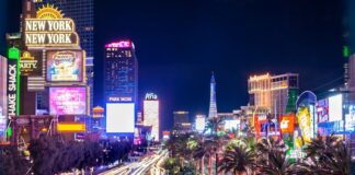 Las Vegas Gaming Win Climbs in October as Visitation Declines for 10th Straight Month Long-exposure night view of the Las Vegas Strip showing casino lights, hotel signs, and traffic streaks.