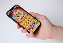 A person holding a smartphone displaying a colorful online slot game.