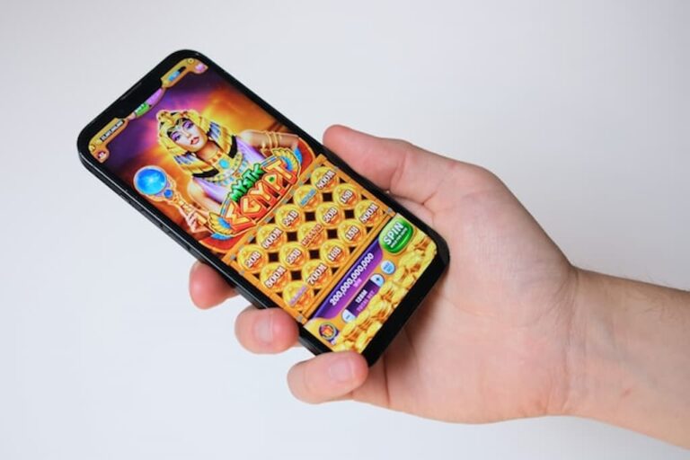 A person holding a smartphone displaying a colorful online slot game.
