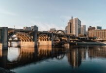 Minnesota AG Warns VGW, Zula & Fortune Coins to Halt Sweepstakes Casinos Bridge and city skyline reflected on a river in Minnesota.