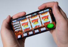 Hands holding a smartphone displaying a generic online slot machine game