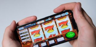 VGW is Preparing to Launch Two New Sweepstakes Casinos: LuckyLand Casino & United Slots Hands holding a smartphone displaying a generic online slot machine game