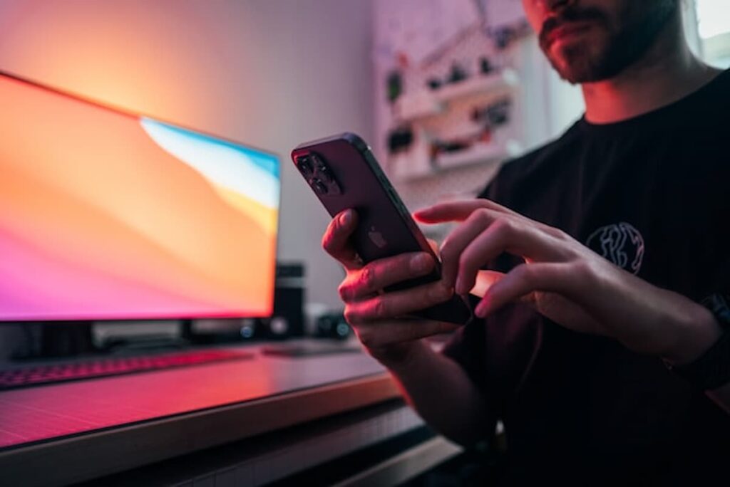 Man in black shirt holding a smartphone.