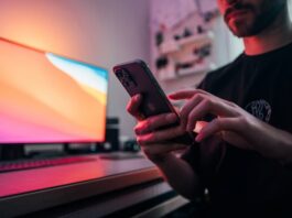 Man in black shirt holding a smartphone.