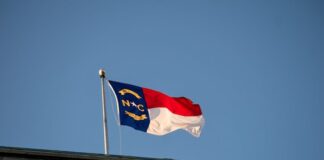 North Carolina PTSO Treasurer Accused of Diverting $300,000 in Funds Into Online Gambling North Carolina state flag waving against a clear blue sky