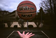 NCAA Bans Six Men’s Basketball Players for Betting-Related Game Manipulation A person tossing an NCAA basketball on an outdoor court.