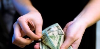 Hands counting US dollar bills.