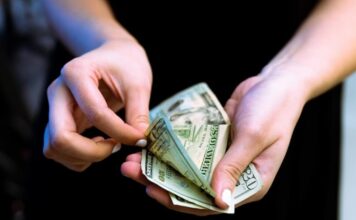 Playtech’s £500K ‘Success Fee’ Arrangement With Black Cube Uncovered in Court Filings Hands counting US dollar bills.