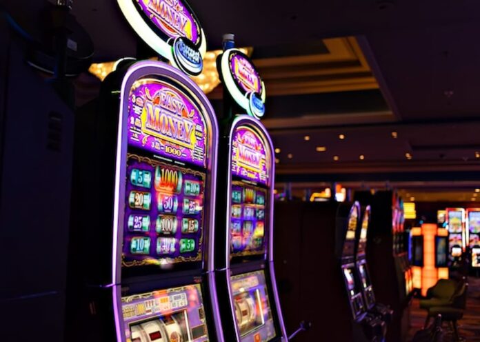 Row of illuminated slot machines inside a casino.