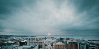 Wisconsin Online Sports Betting Bill Pulled From Assembly, Pushed to 2026 Session A stormy skyline view of Wisconsin's State Capitol surrounded by city blocks and cloudy skies